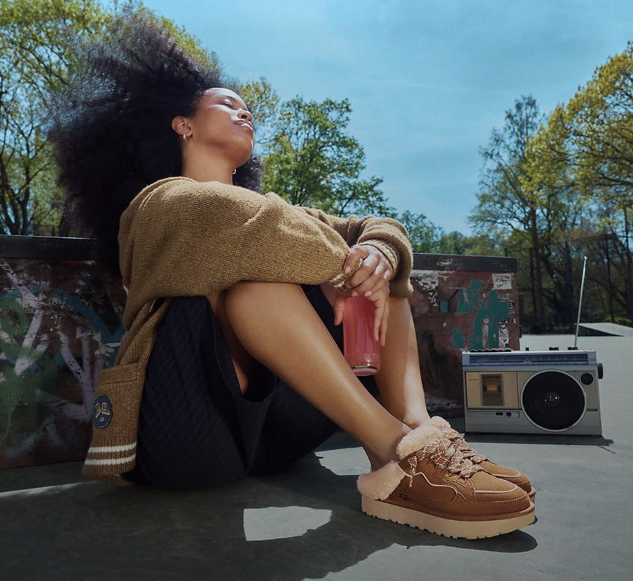 imagen de mujer con sueter cafe pantalon negro y pantuflas cafes de la marca UGG